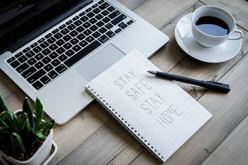 Stay safe stay home text with laptop computer and coffee on wooden background.