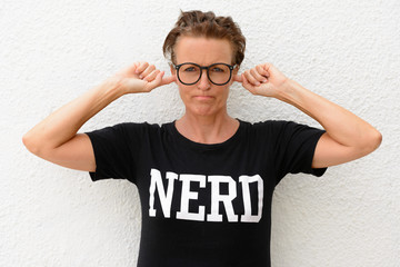 Mature nerd woman wearing big eyeglasses and standing against white background outdoors while...
