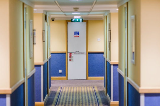 Corridor in a hotel looking down towards a fire escape.