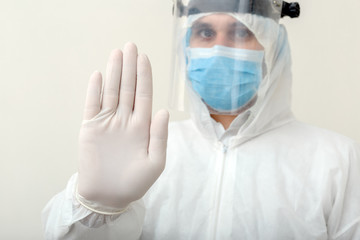 Doctor show sign Stop gesture NO to pandemic of Covid-19, Coronavirus wearing protection suit and face mask on white background. Medical, healthcare social distancing concept.