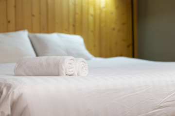 Fototapeta na wymiar White towel on bed in guest room for hotel customer.