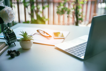 Work online from home Concept, Diary and calendar for Planner to plan and remind daily appointment schedule timetable and management of the job.Cactus laptop and Vintage clock placed on desk.
