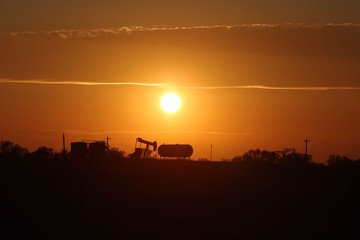 Fototapeta premium Sunsets on Oil industry’s pump jack and tanks