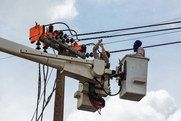 electricians repairing wire of the power line on electric power pole