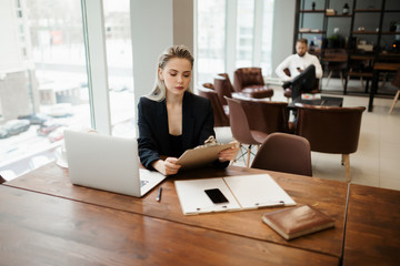 A beautiful girl Manager is sitting in the office at her workplace and is immersed in the workflow