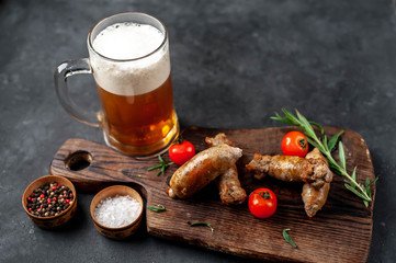 Beer and grilled sausages with spices, tomatoes, rosemary on a stone background with copy space for your text