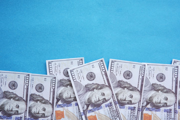 One hundred (100) dollar bills isolated on a blue background.