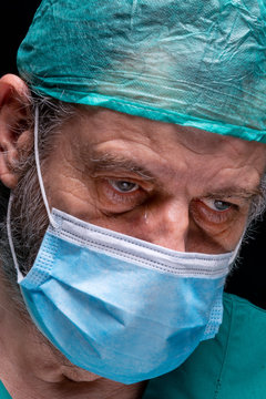 Close-up of the face of a crying doctor, with cap and mask