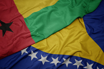 waving colorful flag of bosnia and herzegovina and national flag of guinea bissau.