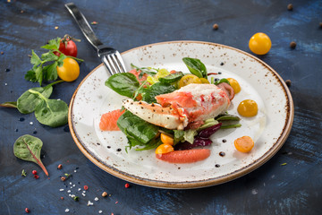 healthy salad with crab meat, claws, grapefruit and tomatoes on white plate blue background © Eduard Zhukov