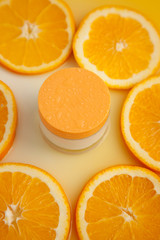 Cosmetic jar with natural energy vitamin skin care. Cosmetic cream on an orange background.