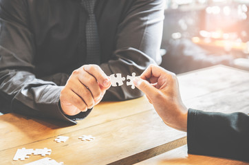 Businesspeople holding white jigsaw puzzle and connect together - obrazy, fototapety, plakaty