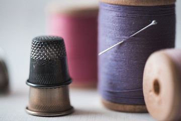 Stack of old thimbles with spool of threads closeup staying on table. Handmade.