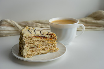 Piece of delicious sweet cake on white plate and a cup of coffee on light background