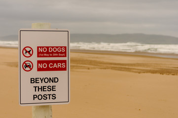 Sign on a beach warning that no dogs or cars are permitted beyond this point.
