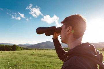 Fototapeta na wymiar Young man at mountain looking through binoculars