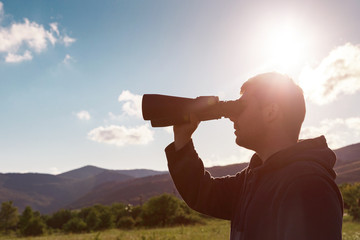 Fototapeta na wymiar Young man at mountain looking through binoculars
