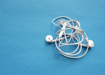 Tangled wired headphonTangled wired headphones on a blue background. Old wired technology.es on a...