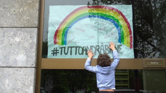Europe, Italy , Milan  -  Boy children five years old touch  the inscription everything will be fine ( tutto andra' bene )during n-cov19 Coronavirus epidemic - quarantine life style - flash mob