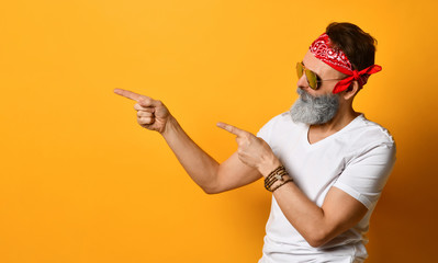 Mature male in sunglasses, red bandana, white t-shirt, bracelet. Pointing at something by...