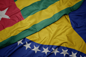 waving colorful flag of bosnia and herzegovina and national flag of togo.