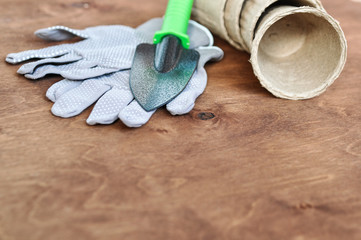 Spring set for seedlings in the garden consisting of gray gloves, a metal shovel and peat pots on a...