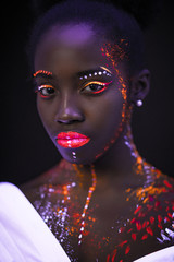 unusual shoot of fashion model woman in neon light. portrait of young beautiful model girl with fluorescent makeup. Body art design in UV, painted face, colorful make up on skin