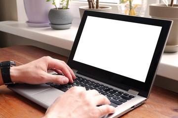 A man in a plaid shirt uses a laptop with a white screen isolated. A blank for placing your information on a computer screen.