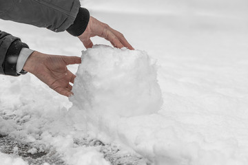 A man makes a snowman in a winter day