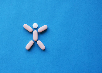 Medical pills in the shape of a man on a blue background.