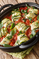 Zucchini roll stuffed with ricotta and baked in tomato sauce in a pan close-up. vertical
