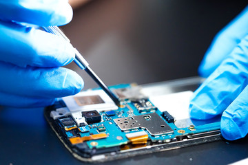 Asian Technician repairing micro circuit main board of smartphone electronic technology : computer,...