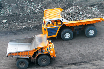 Heavy truck in a quarry transports coal loading excavator