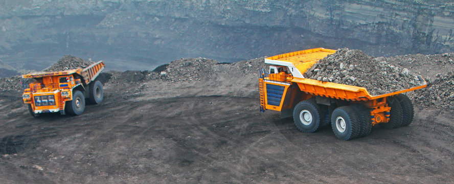 Heavy truck in a quarry transports coal loading excavator