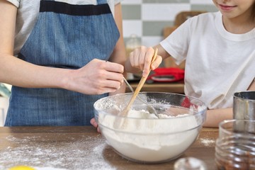 Children mix flour in bowl, add ingredients