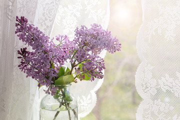 Bright blooms of spring lilacs on the window in house. Spring purple flowers close-up on the blurred background. Selected focus.