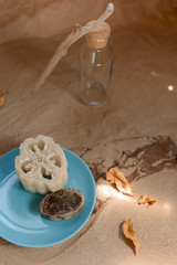 Luffa sponge on a ceramic blue trowel. Background sand and craft paper.