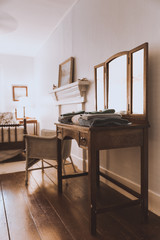 Empty guest room in a boutique hotel, shabby chic style. Freshly laundered towels stacked on wooden vintage dressing table