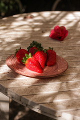 Harvest strawberry on a white wooden table in the garden close up.