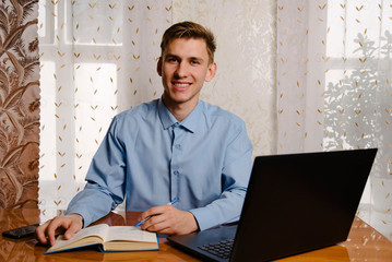 A male freelancer works online on a laptop at home at a Desk