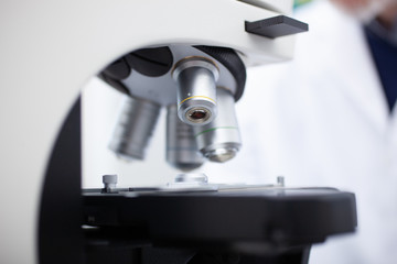 Man using microscope in laboratory, coronavirus medical research concept