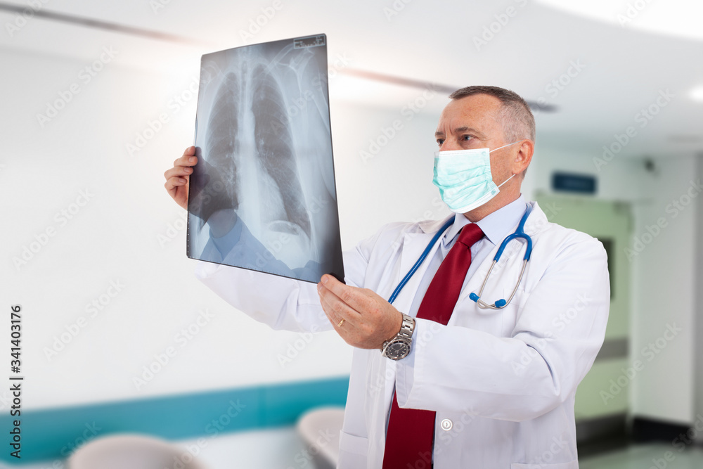 Canvas Prints Masked doctor holding a lung radiography, coronavirus and pneumonia concept