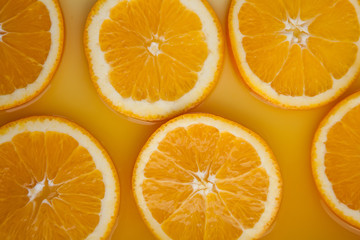 Round fresh orange slices, summer yellow background.