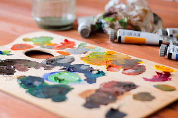 Close up oil painting process. Oil paints palette. Oil painting tools on the wooden table. Painter...