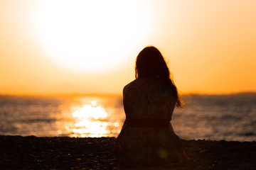 Silhouette of a woman sitting during a sunset
