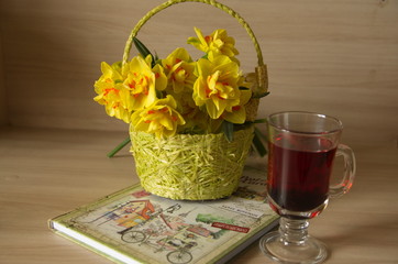 On the table is a yellow basket with flowers of narcotics, a glass cup of tea, a notebook, an envelope.