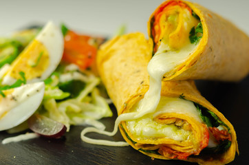 Tomato tortilla wrap with mozzarella cheese,  tomatoes, rocket, basil pesto,  and mix salad