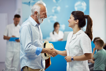 Fototapeta premium Happy senior man greeting with his female doctor at medical clinic.