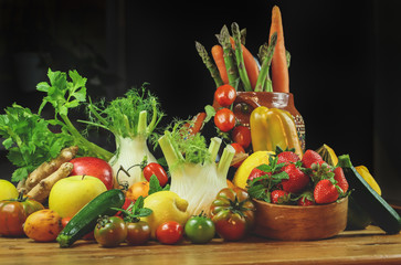 
rustic composition of fruit and vegetables with typical Mexican vase on wooden table illuminated by a warm light