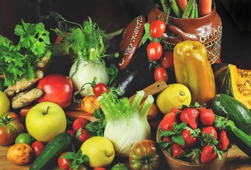 
rustic composition of fruit and vegetables with typical Mexican vase on wooden table illuminated by a warm light